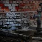 Alte Handpumpe vor einer Backsteinwand